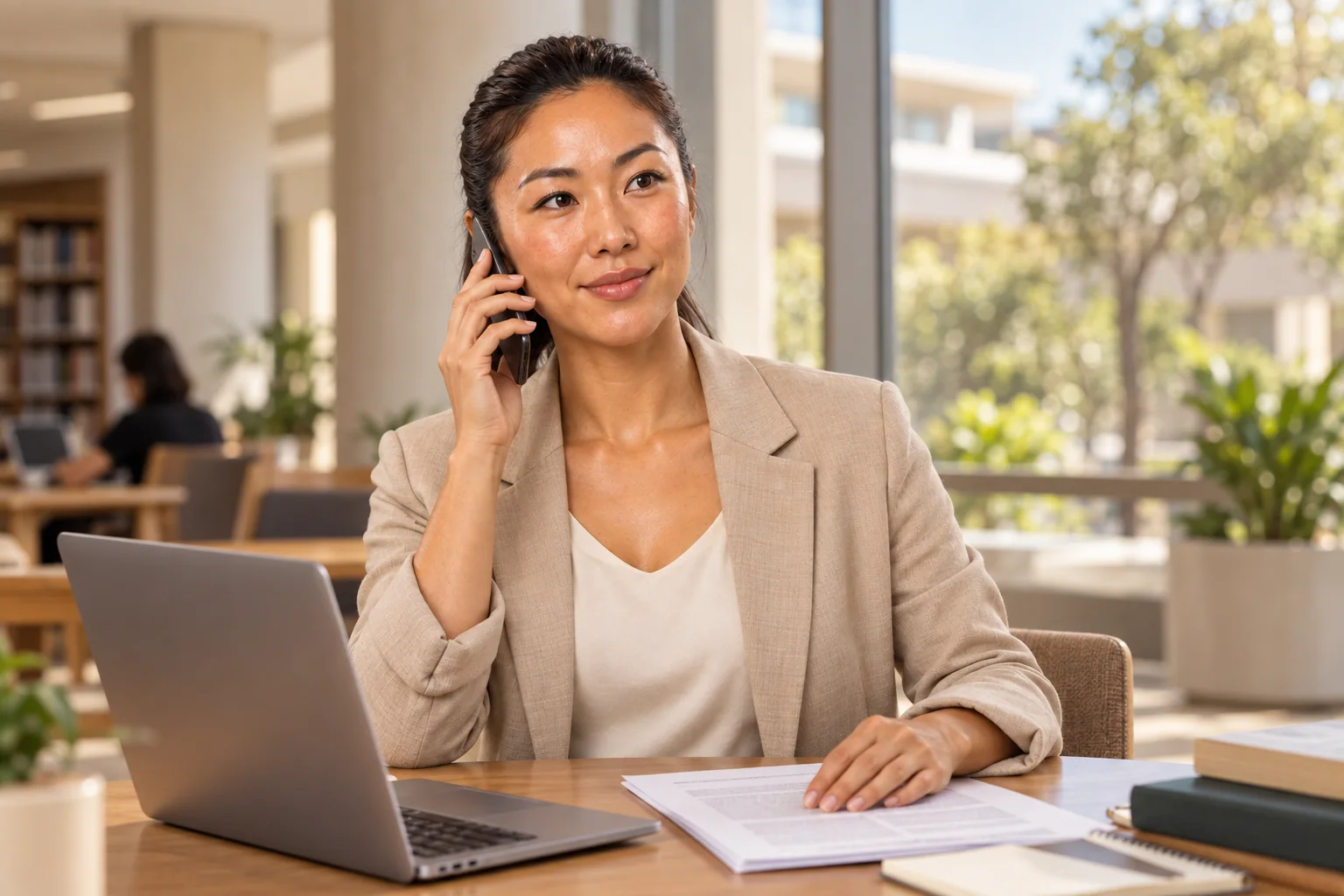 Modelo em uma conversa por telefone sobre publicação científica, com seu artigo e notebook à mesa.